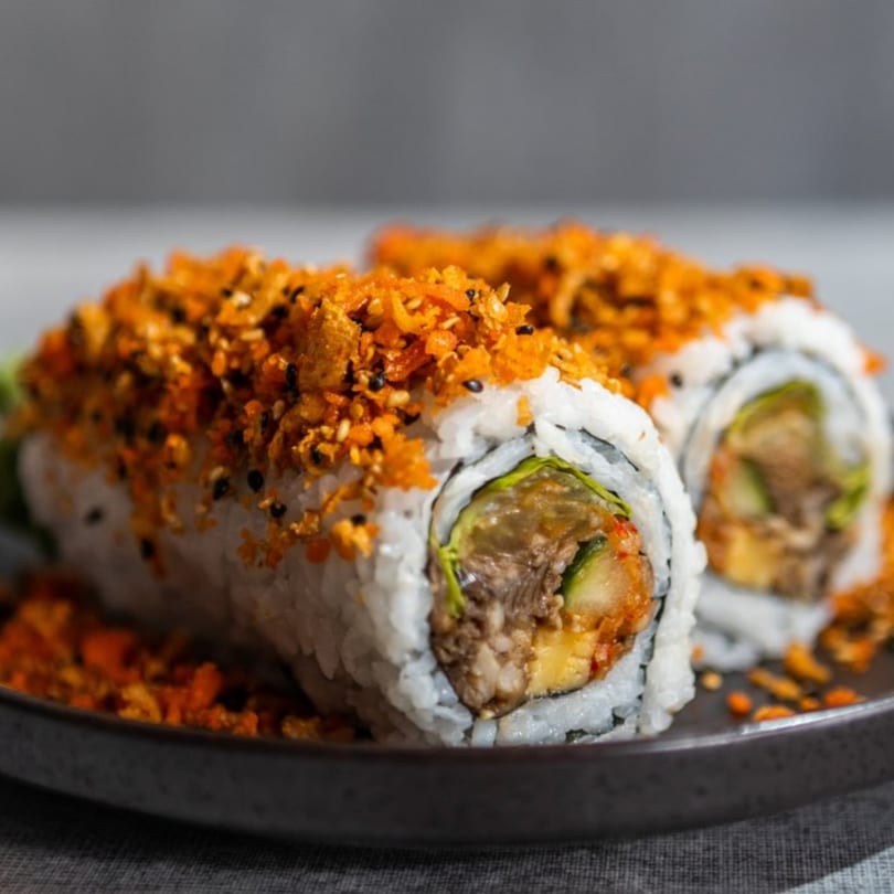 Two Iro Sushi "Stuff x Roll" sushi rolls, topped with orange crispy flakes and black sesame seeds.